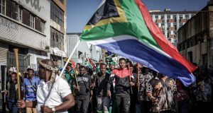 Xenophobia: FG Urges South Africa To Take Concrete Action Against Attacks On Nigerians Protesters hold sticks and flags while chanting slogans as they march during a demonstration by the "March and March" and Operation Dudula movements marking an unofficial deadline set by citizen-led groups for undocumented foreign nationals to leave South Africa, in Johannesburg, on June 30, 2026. South African police deployed to head off unrest and protests on June 30, 2026, the unofficial deadline set by anti-immigrant groups for undocumented foreign nationals to leave that has already pushed thousands to flee. Officers were out in force to prevent violence and looting by the xenophobic groups, while hundreds of foreign nationals took refuge in several cities, urgently seeking help to leave. (Photo by EMMANUEL CROSET / AFP)